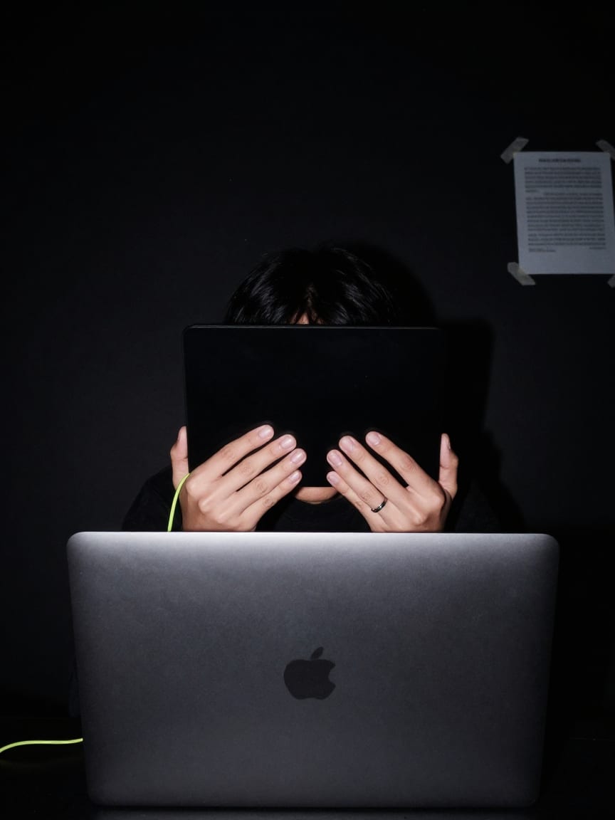 Flash portrait of the night shift keeper behind a laptop lid